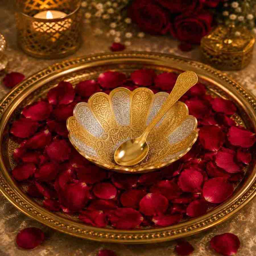 Ornate gold bowl and spoon set on a rose petal-covered tray