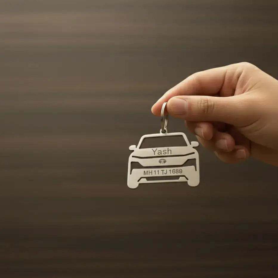 Personalized car-shaped keychain with custom name and vehicle number held in hand on a brown background.