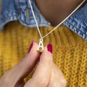 925 silver initial necklace displayed on a model holding the letter A pendant
