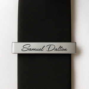 Silver custom engraved tie clip with personalized name on black tie