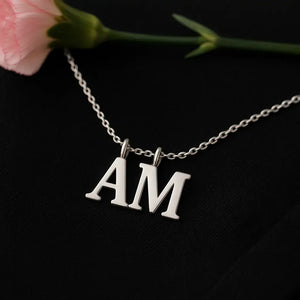 Silver dual letter necklace “AM” pendant on black background – personalized initial jewelry