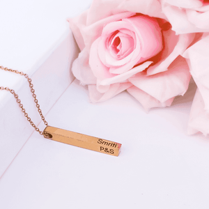 Ankx.in gold Bar Name Necklace with custom engraving placed next to soft pink roses
