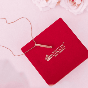 Gold bar name necklace with custom engraving on chain displayed on red Ankx.in jewelry box