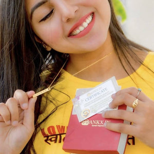 Woman wearing a gold Bar Name Necklace from Ankx.in holding a certificate and jewelry box
