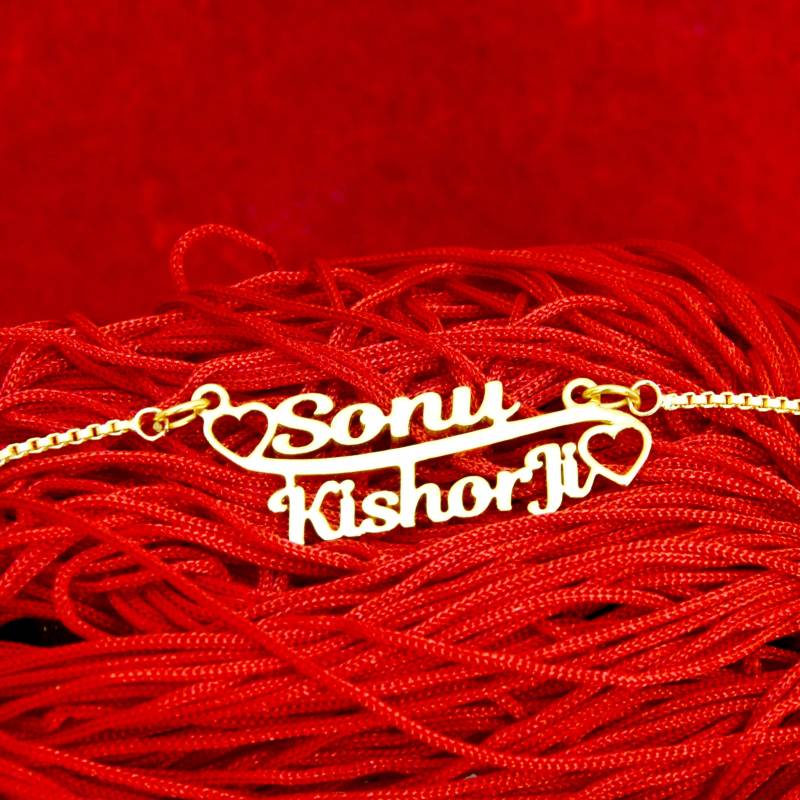 Gold couple name necklace with names Sony and Kishori heart design on red fabric background