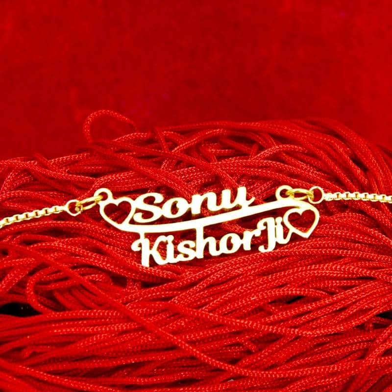 Gold couple name necklace with names Sony and Kishori heart design on red fabric background