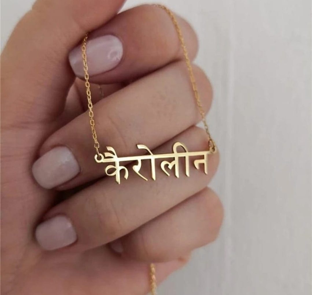 Gold Hindi Name Necklace with custom Hindi script held by hand with light pink nails