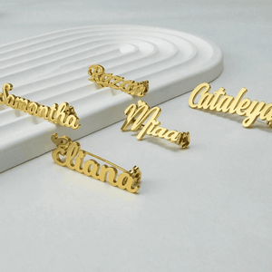 Collection of personalized name lapel pins displayed on a sleek surface featuring various names in gold