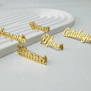 Collection of personalized name lapel pins displayed on a sleek surface featuring various names in gold