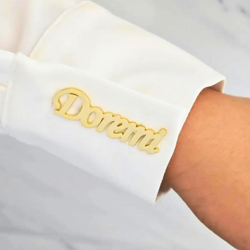 Personalized name lapel pin in gold featuring the name Doremi worn on a white shirt sleeve