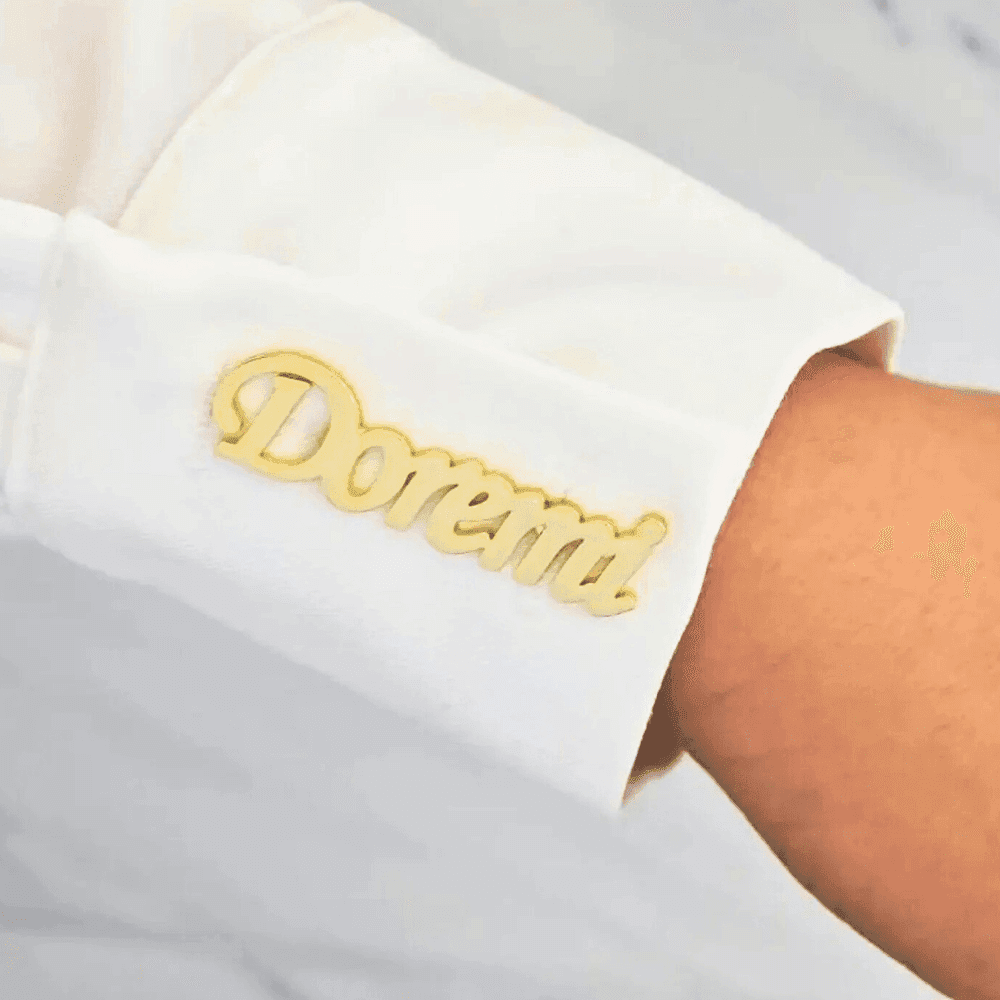 Personalized name lapel pin in gold featuring the name Doremi worn on a white shirt sleeve
