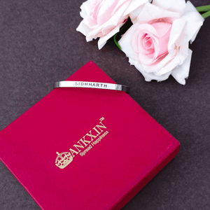 Ankx.in personalized silver Name Bracelet with custom engraving on a red box beside pink roses