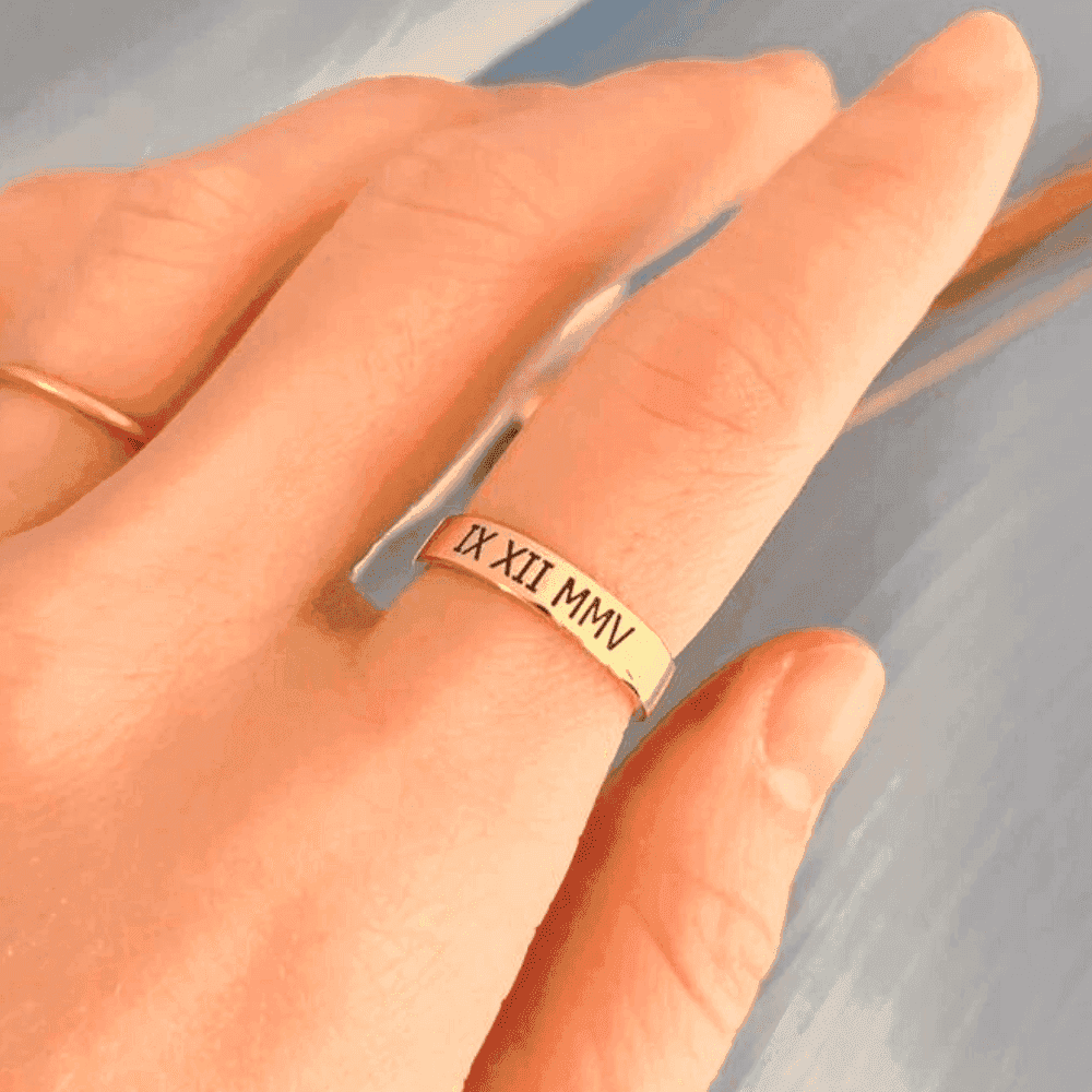 Ankx.in gold name ring with Roman numeral engraving worn on finger