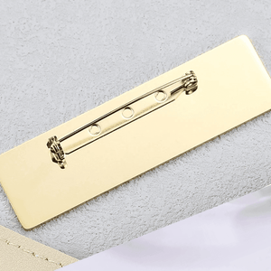 Close-up of a gold engraved metal name brooch with secure pin fastening for custom personalization