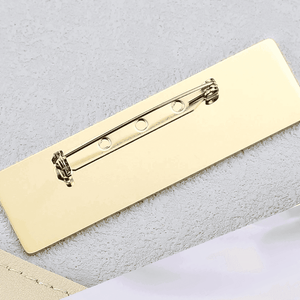 Close-up of a gold engraved metal name brooch with secure pin fastening for custom personalization