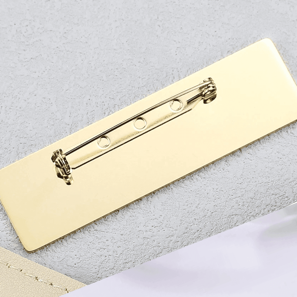 Close-up of a gold engraved metal name brooch with secure pin fastening for custom personalization