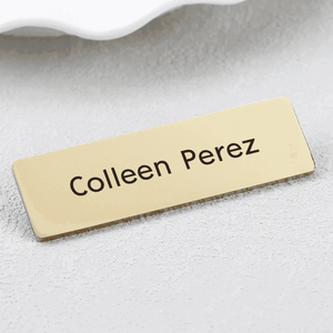 Personalized engraved metal name brooch featuring gold finish with bold lettering for custom styling