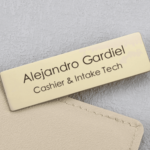 Engraved metal name brooch featuring a gold finish with personalized name and title display