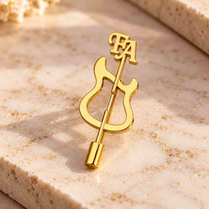 Gold personalized guitar brooch displayed on a luxury beige marble surface with FA initials