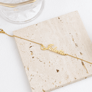 Custom name anklet in gold with Juliette lettering on a textured surface