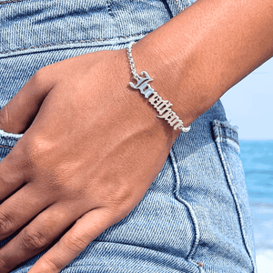 Custom name bracelet in silver design worn on a wrist against a beach backdrop