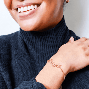 Custom name chain bracelet worn on a woman's wrist, adding a personal touch to her outfit