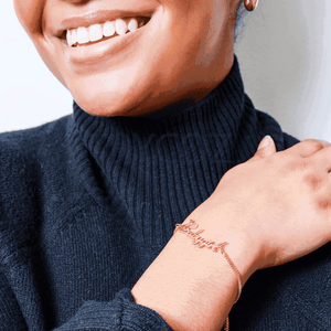 Custom name chain bracelet worn on a woman's wrist, adding a personal touch to her outfit