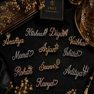 Assorted personalized name pins with charms displayed on a black background.