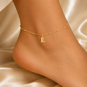 Gold initial anklet with letter E charm worn on ankle