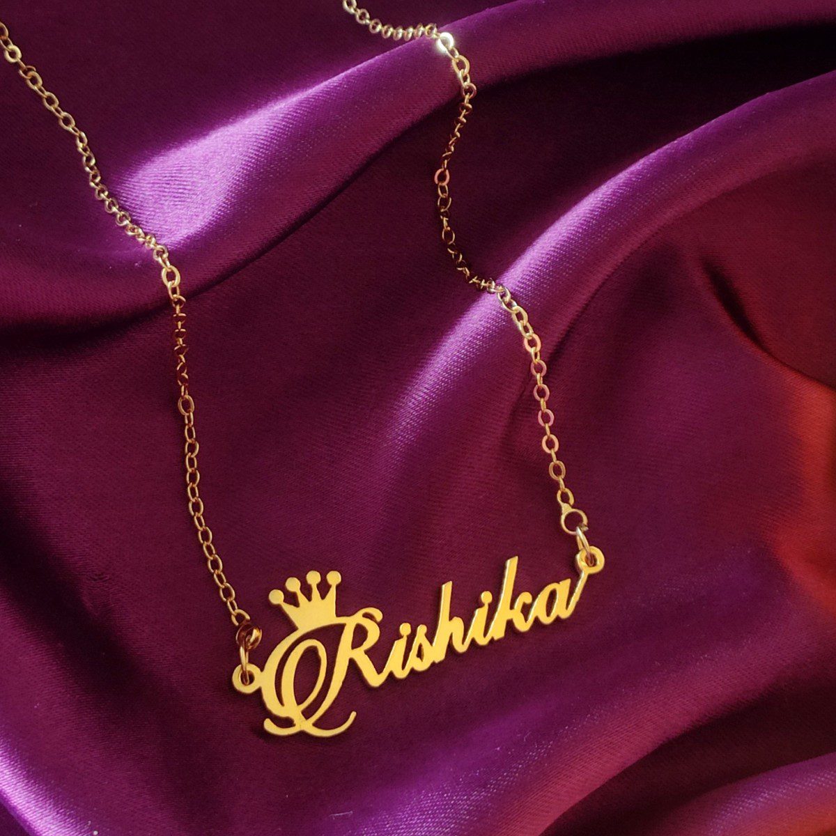Gold Name Necklace With Crown featuring the name Rishika on a luxurious backdrop