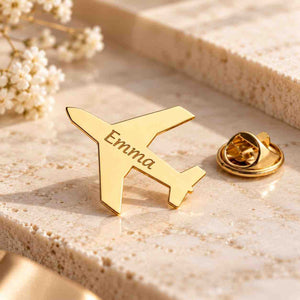 Personalized gold airplane brooch engraved with Emma on a premium marble surface