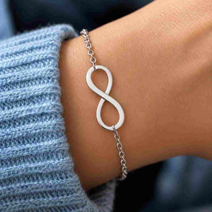 Silver infinity bracelet worn on a wrist with a light blue knitted sleeve