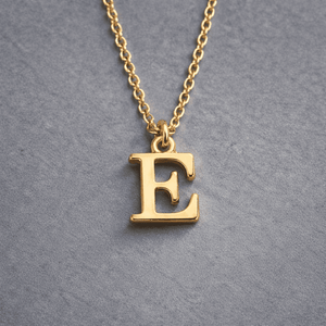 Gold Initial Letter Necklace Alphabet E Pendant with Delicate Chain on Grey Background