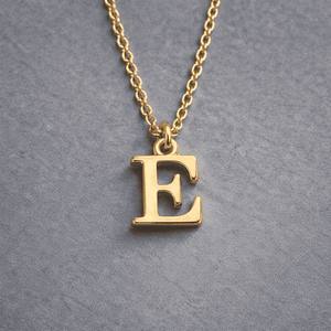 Gold Initial Letter Necklace Alphabet E Pendant with Delicate Chain on Grey Background
