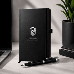Custom branded notebook standing on office desk beside laptop and matching logo pen