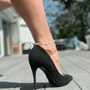 Minimal silver anklet for women showcased on a foot wearing stylish high heels outdoors