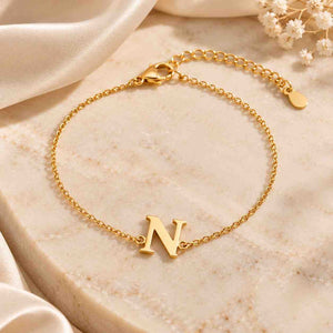 Gold N initial bracelet displayed on cream marble with delicate chain, clasp and adjustable extension