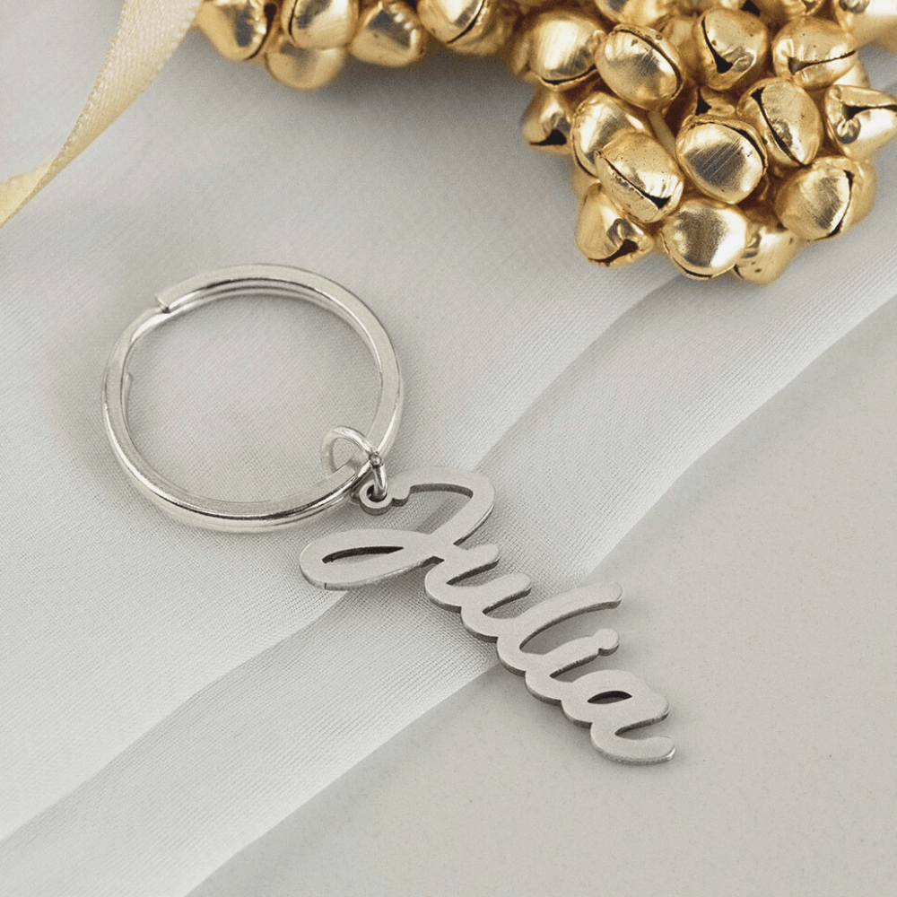 Silver custom Name Keychain with the name Julia in cursive script on a white fabric background
