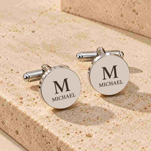 Personalized silver round cufflinks with engraved initial and name on a wedding surface