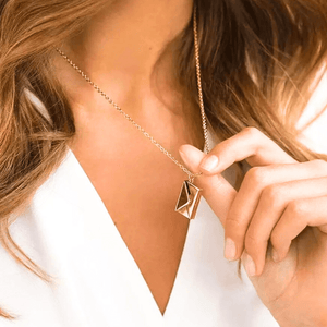 Gold Secret Message Letter Envelope Necklace worn by woman with white top and light brown hair