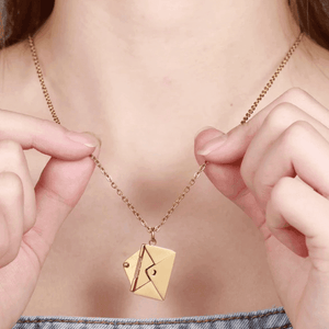 Secret Message Letter Envelope Necklace in gold tone worn close-up on model holding the chain
