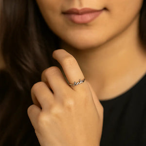 Woman wearing a silver custom name ring with personalized text on her finger
