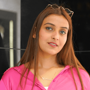 Woman modeling a unique gift custom name jewelry necklace made by Ankx.in in a stylish pink outfit