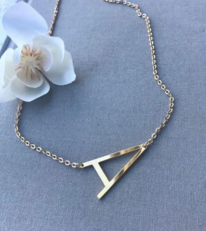 Custom Alphabet Necklace Large gold letter A pendant on delicate chain from Ankx.in displayed on gray fabric