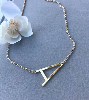 Custom Alphabet Necklace Large gold letter A pendant on delicate chain from Ankx.in displayed on gray fabric