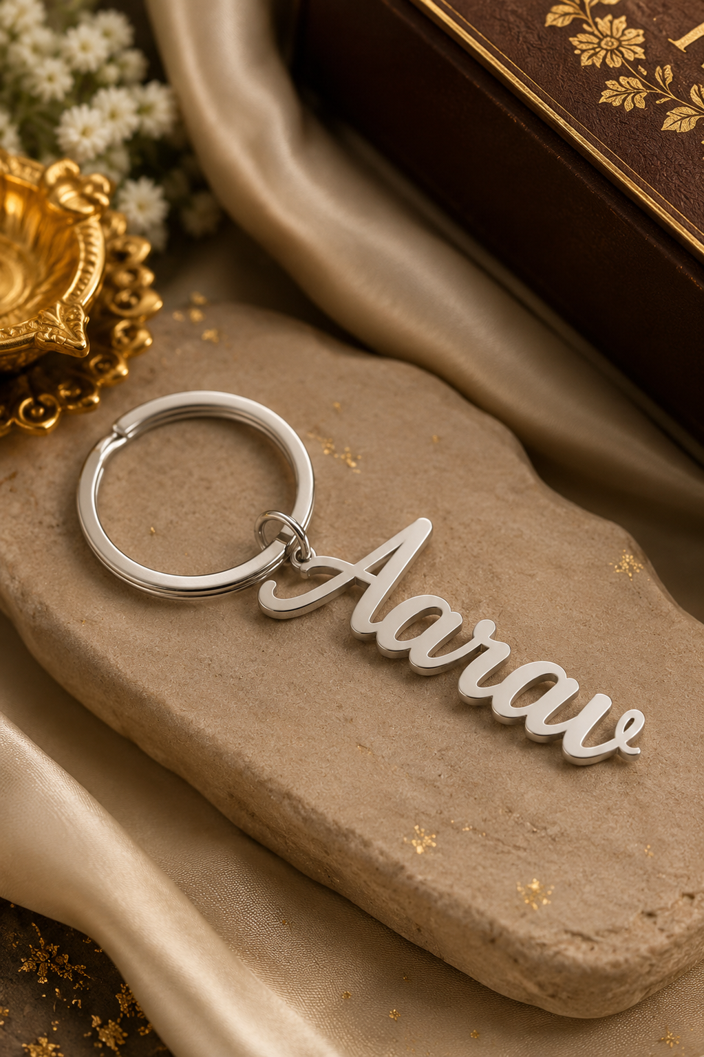 Custom metal name keychain engraved "Aarav" in cursive font, styled flat lay with festive gold decor