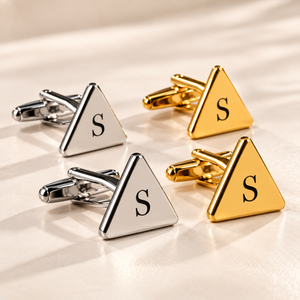 Personalized silver and gold triangular cufflinks with black engraved S initials on a luxury white surface