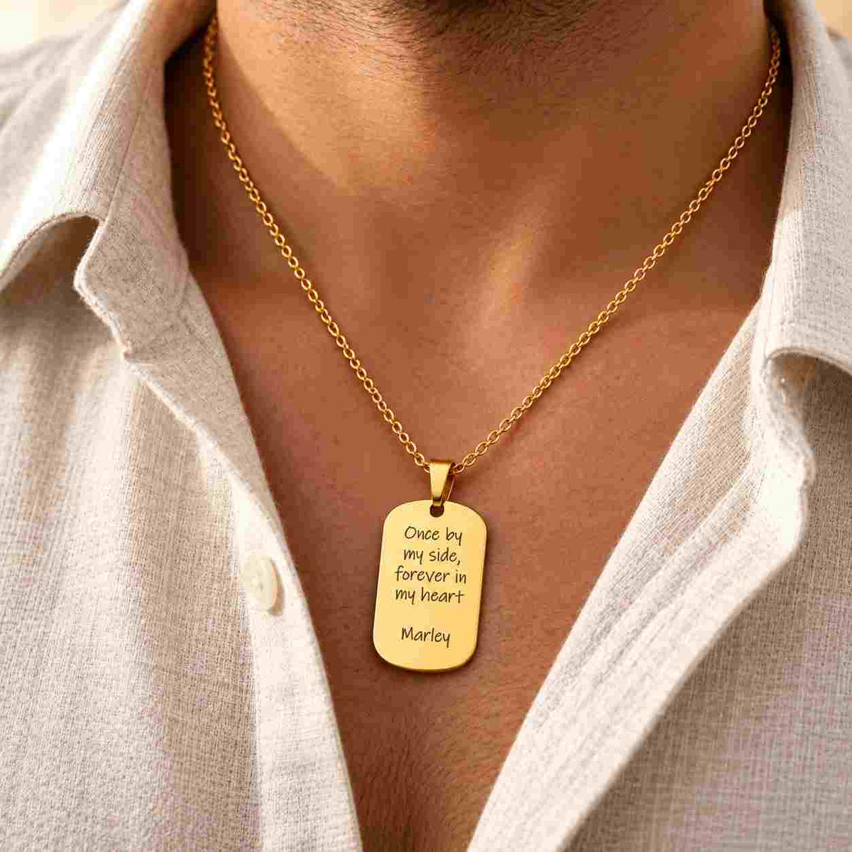 Gold personalized dog tag necklace worn by a man with “Once by my side, forever in my heart” and “Marley” engraved on the pendant.