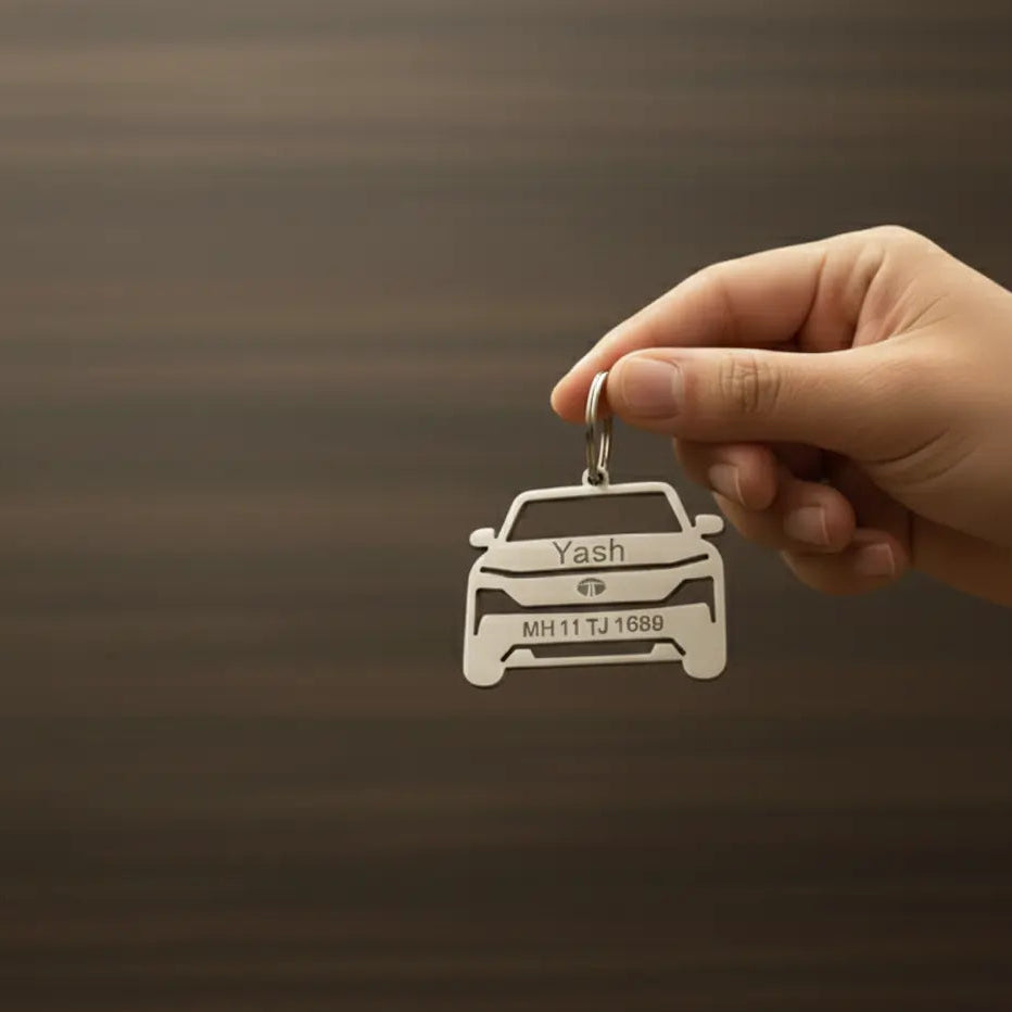 Personalized car-shaped keychain with custom name and vehicle number held in hand on a brown background.