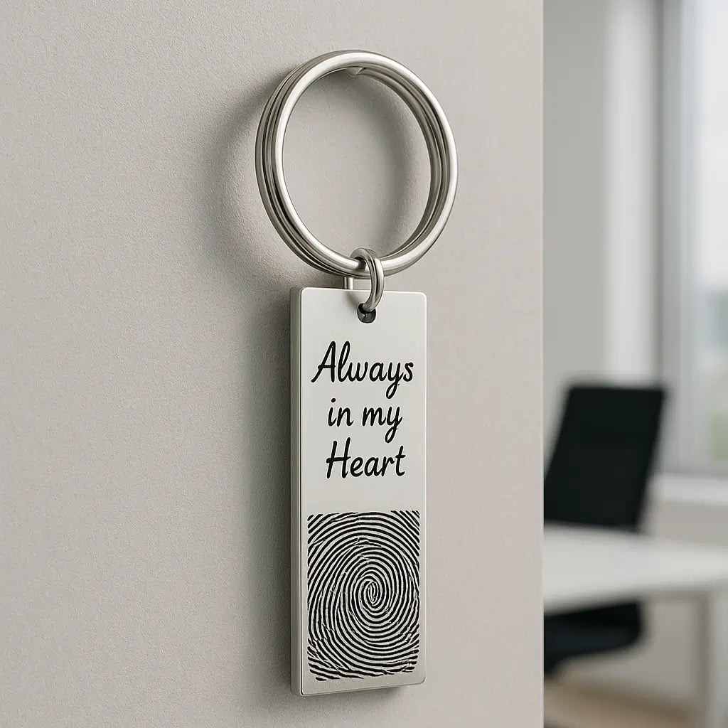 Silver fingerprint keychain engraved with “Always in my Heart” hanging on a wall